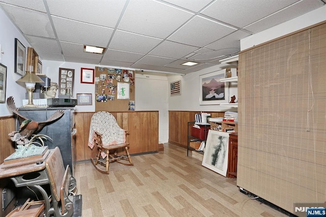 interior space featuring a paneled ceiling, a wainscoted wall, wooden walls, and wood finished floors