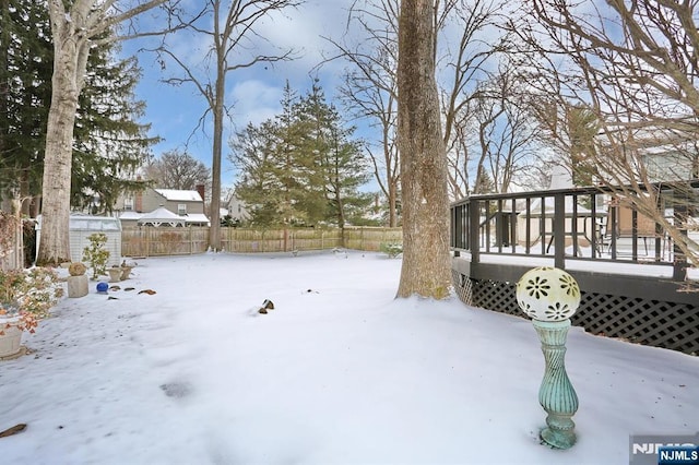 yard layered in snow featuring fence and a wooden deck