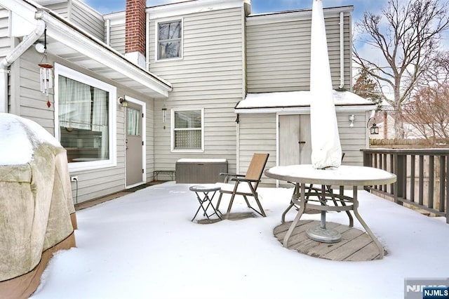 snow covered patio featuring outdoor dining space and fence