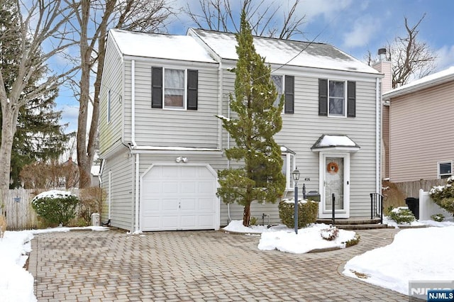 view of front facade featuring decorative driveway, fence, and an attached garage