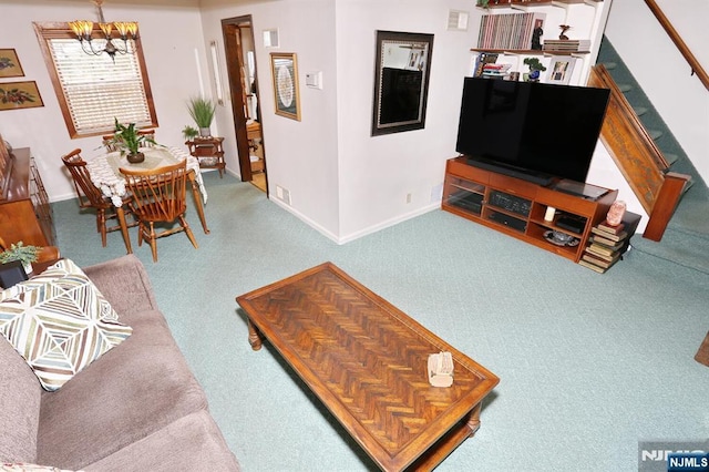 carpeted living area featuring a chandelier, stairs, visible vents, and baseboards