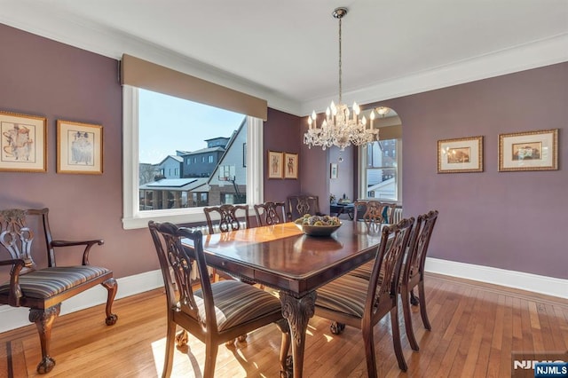 dining area featuring an inviting chandelier, crown molding, baseboards, and hardwood / wood-style flooring