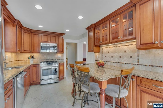 kitchen featuring a sink, stainless steel appliances, light stone counters, and light tile patterned floors