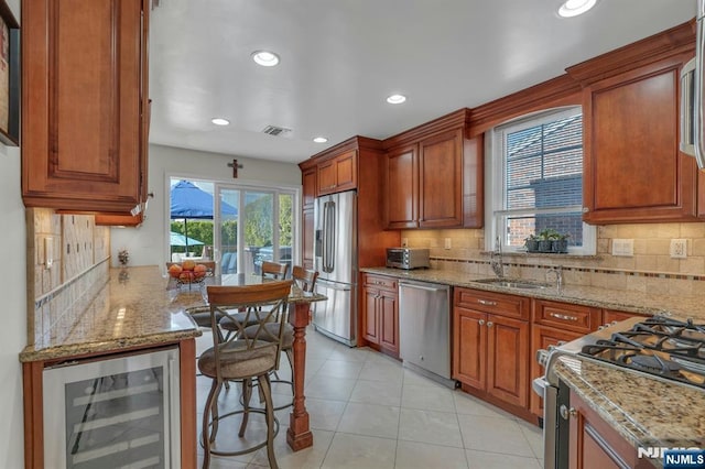 kitchen featuring a sink, stainless steel appliances, wine cooler, and light stone counters