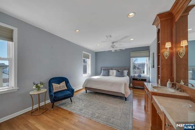 bedroom with visible vents, wood finished floors, baseboards, and a sink