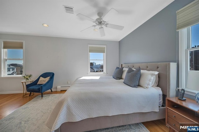 bedroom with wood finished floors, visible vents, baseboards, vaulted ceiling, and baseboard heating