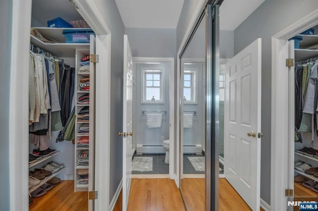 spacious closet featuring light wood-style floors and baseboard heating