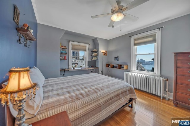 bedroom featuring a ceiling fan, radiator, wood finished floors, and crown molding