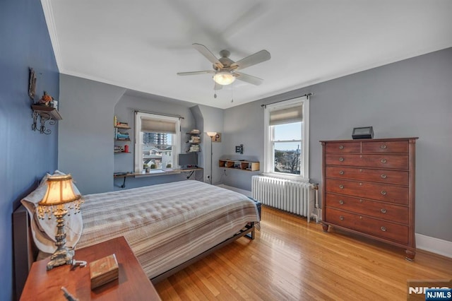 bedroom featuring ceiling fan, baseboards, radiator heating unit, ornamental molding, and wood finished floors