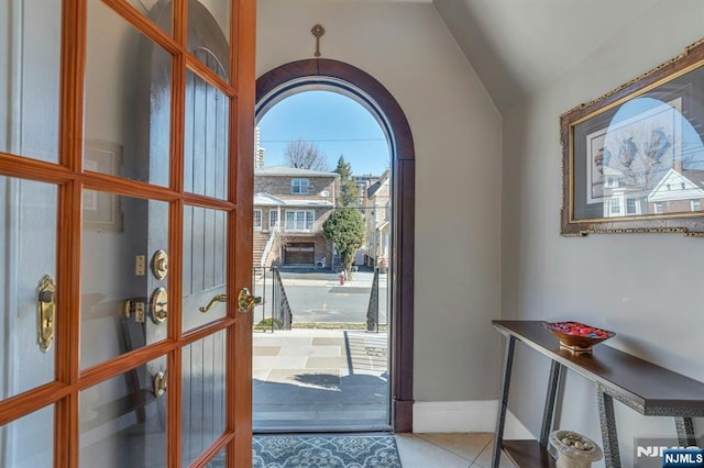 tiled entrance foyer featuring baseboards and vaulted ceiling