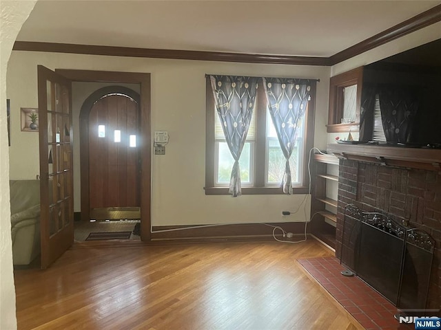 entrance foyer with arched walkways, baseboards, wood finished floors, and crown molding