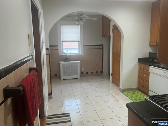 kitchen with dishwasher, dark countertops, ceiling fan, tile walls, and light tile patterned flooring