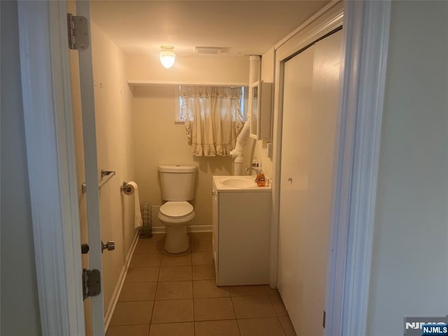 half bathroom with visible vents, toilet, vanity, baseboards, and tile patterned floors