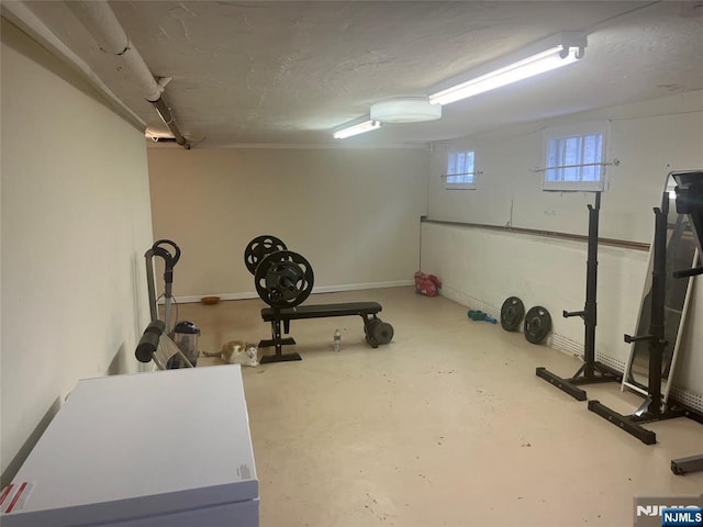 workout room with a textured ceiling and baseboards