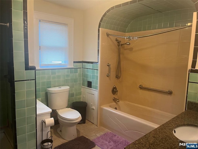 full bath with tile patterned flooring, toilet, bathing tub / shower combination, vanity, and tile walls