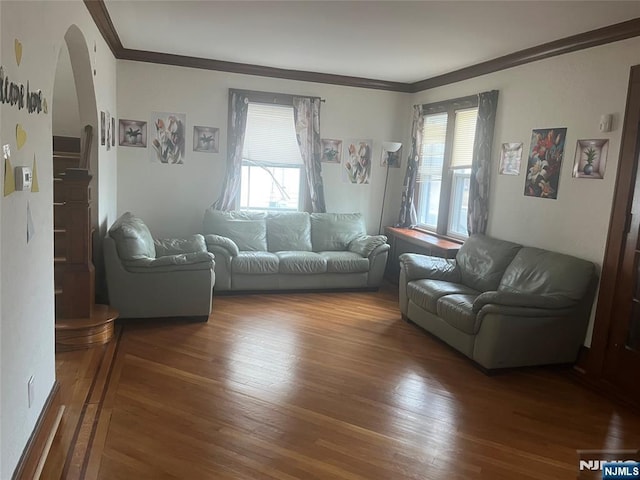 living area featuring ornamental molding, arched walkways, and wood finished floors