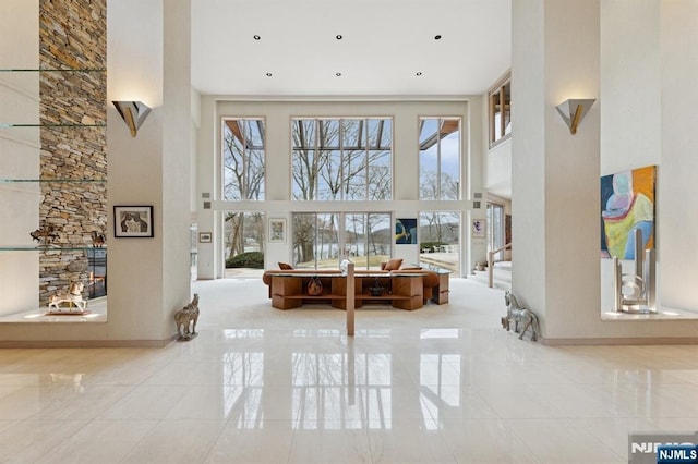 living room featuring a high ceiling, tile patterned flooring, a wealth of natural light, and baseboards