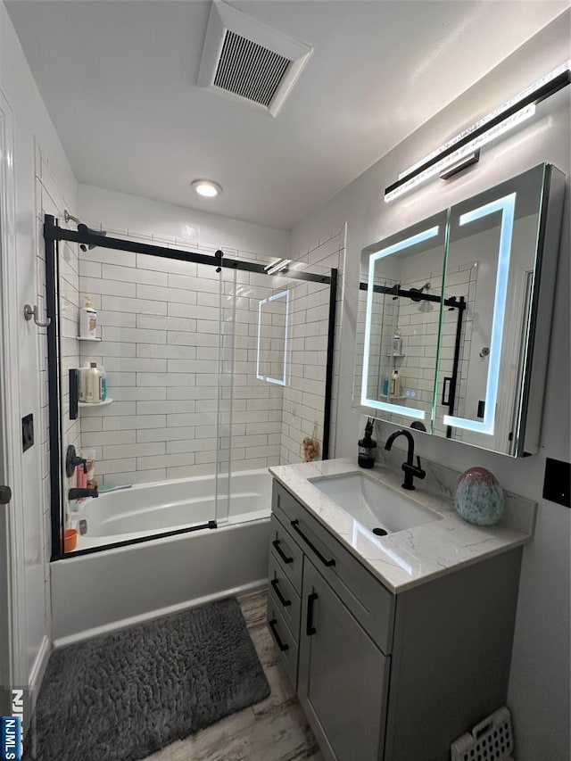 bathroom featuring radiator, visible vents, vanity, and combined bath / shower with glass door