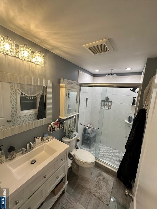 bathroom with toilet, a stall shower, vanity, and visible vents