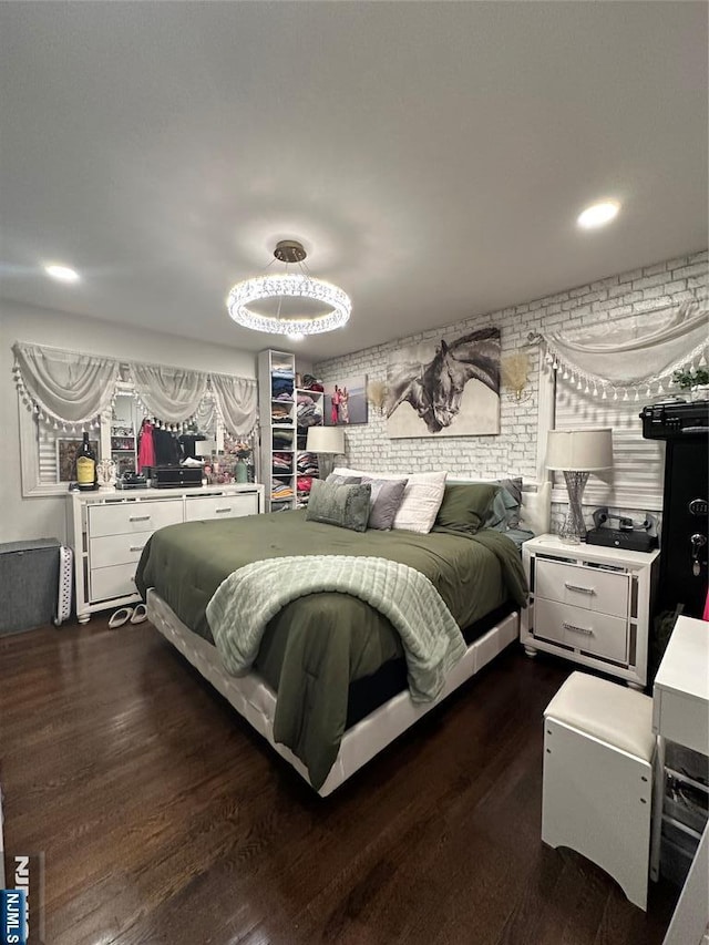 bedroom with brick wall and dark wood-type flooring