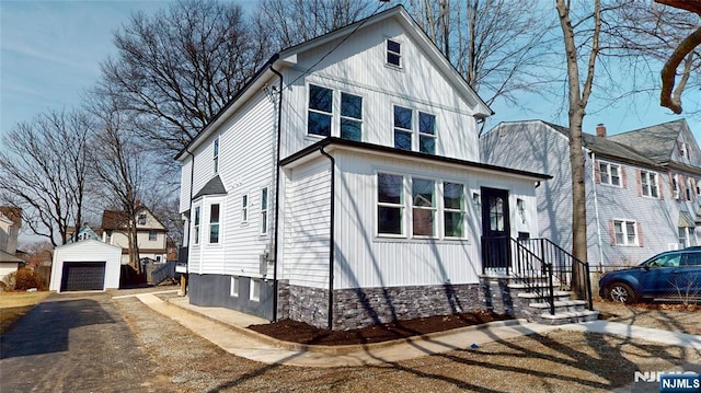 view of front facade featuring aphalt driveway, an outbuilding, and a detached garage