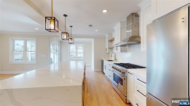 kitchen with a center island, recessed lighting, appliances with stainless steel finishes, a sink, and wall chimney range hood