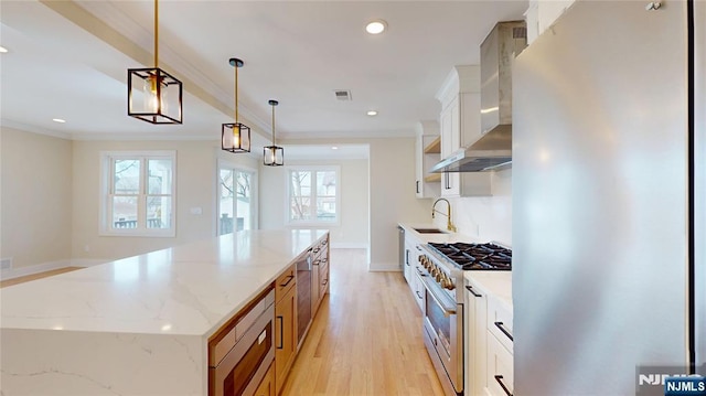 kitchen with appliances with stainless steel finishes, crown molding, a sink, and wall chimney range hood