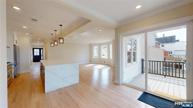 kitchen featuring a center island, decorative light fixtures, light wood finished floors, ornamental molding, and freestanding refrigerator