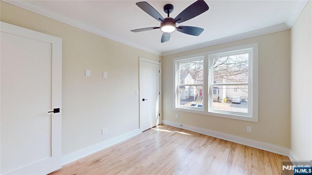 empty room featuring ornamental molding, light wood-type flooring, a ceiling fan, and baseboards