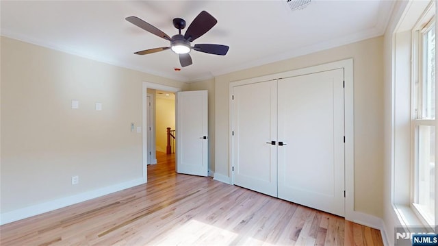 unfurnished bedroom with crown molding, a closet, light wood-type flooring, and baseboards