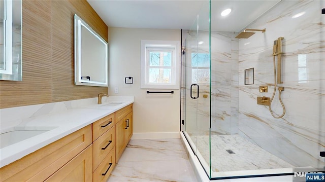 bathroom with double vanity, marble finish floor, a marble finish shower, and a sink