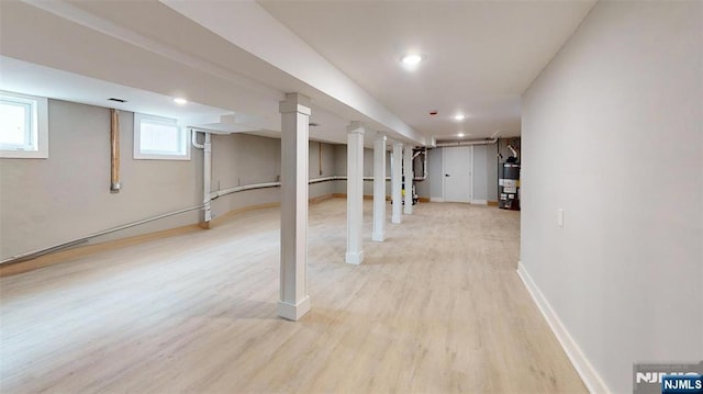 basement with recessed lighting, light wood-style flooring, baseboards, and electric water heater