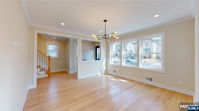 empty room featuring light wood-style floors, baseboards, stairway, and visible vents