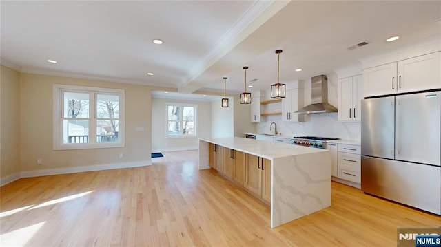 kitchen with wall chimney range hood, stainless steel fridge, light wood-style floors, and crown molding