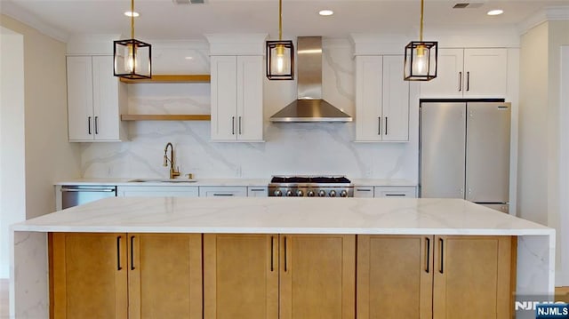 kitchen featuring stainless steel appliances, decorative backsplash, a sink, wall chimney range hood, and a kitchen island