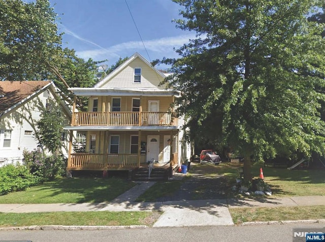view of front of house featuring covered porch, a balcony, and a front lawn