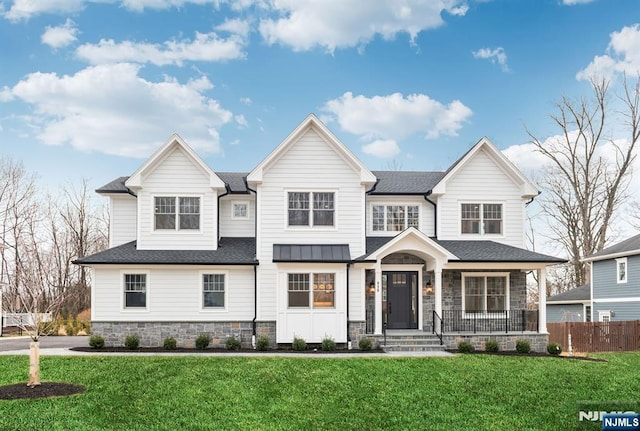 view of front facade featuring stone siding, fence, and a front lawn