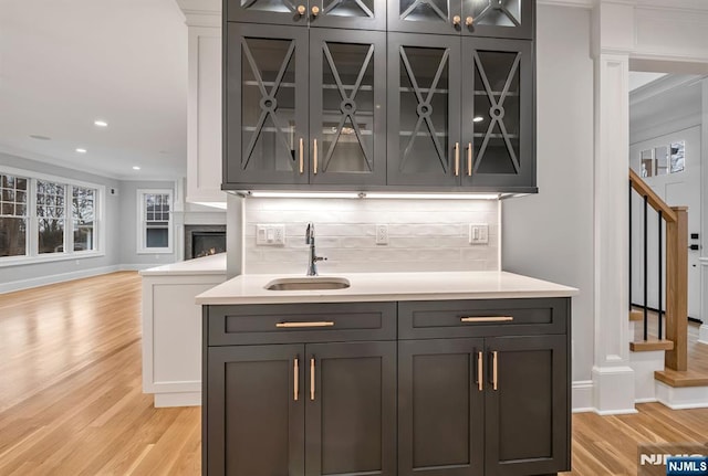 bar featuring stairs, backsplash, a sink, and light wood-style floors