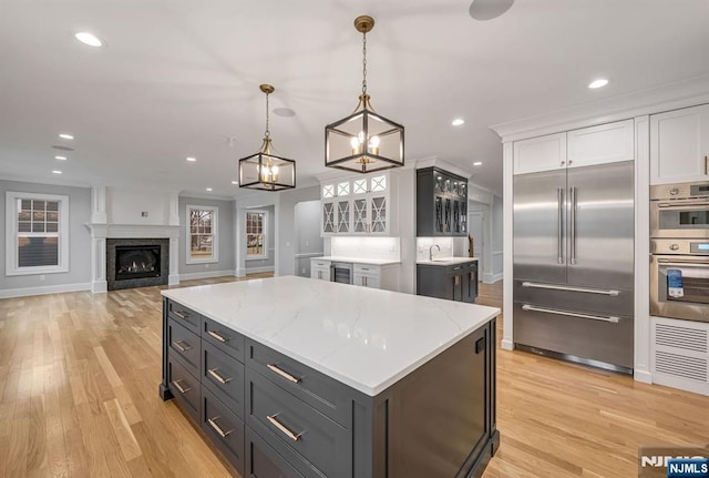 kitchen featuring recessed lighting, a fireplace, white cabinets, appliances with stainless steel finishes, and light wood finished floors