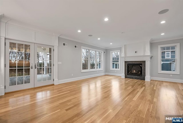 unfurnished living room with light wood-style flooring, recessed lighting, visible vents, ornamental molding, and a glass covered fireplace