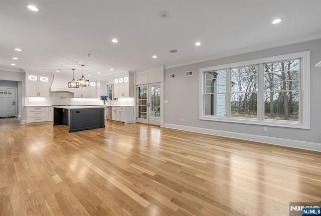 unfurnished living room featuring light wood-style floors, recessed lighting, crown molding, and baseboards