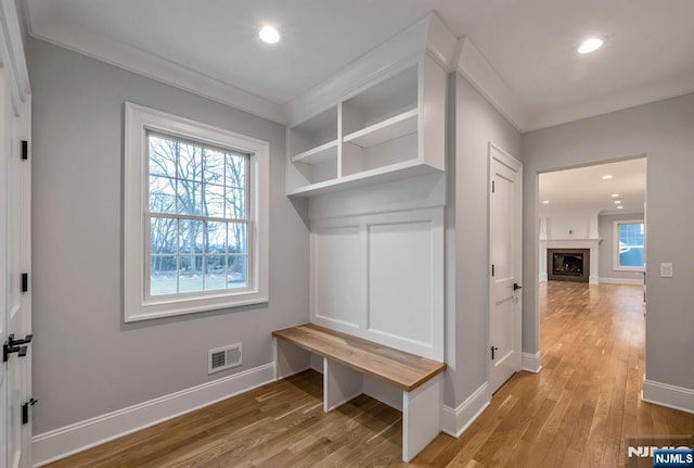 mudroom with light wood finished floors, plenty of natural light, ornamental molding, and baseboards