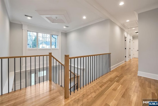 corridor with visible vents, attic access, ornamental molding, wood finished floors, and baseboards