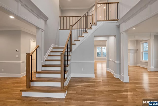 stairs featuring baseboards, wood finished floors, and crown molding