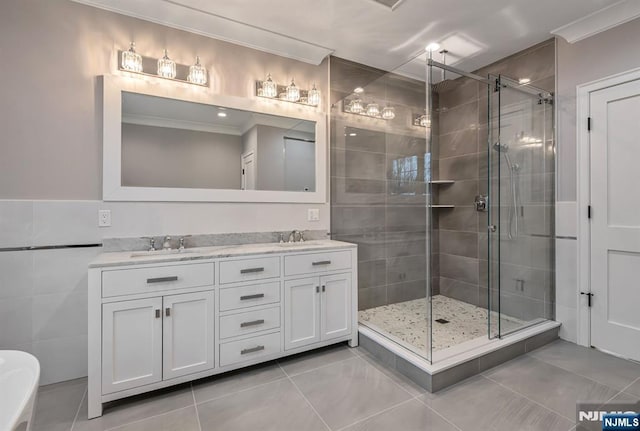 bathroom featuring double vanity, ornamental molding, tile patterned flooring, a shower stall, and a sink