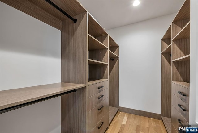 walk in closet with light wood-style floors