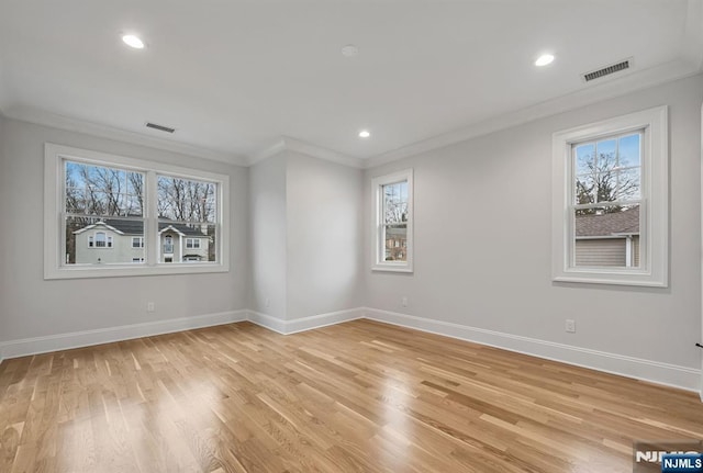 empty room featuring light wood finished floors, baseboards, visible vents, and crown molding