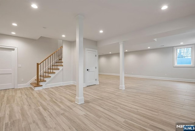 below grade area with light wood-style floors, recessed lighting, stairway, and baseboards