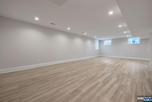 below grade area with recessed lighting, light wood-style flooring, and baseboards