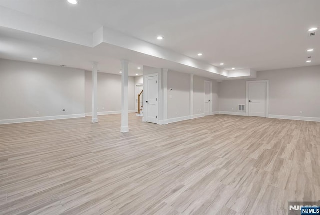 finished basement featuring light wood-style flooring, recessed lighting, visible vents, baseboards, and stairs